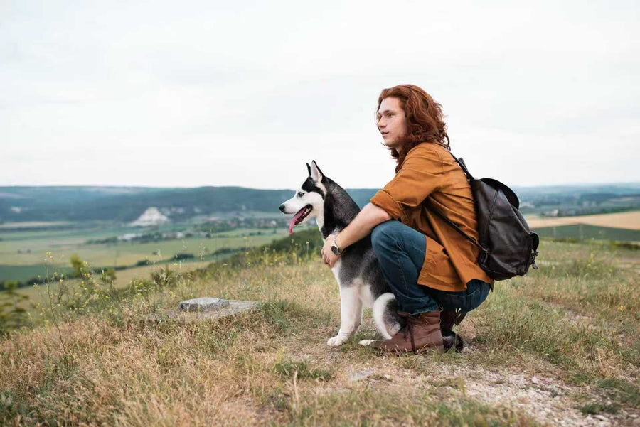 Man hiking with his Siberian Husky on a scenic hilltop